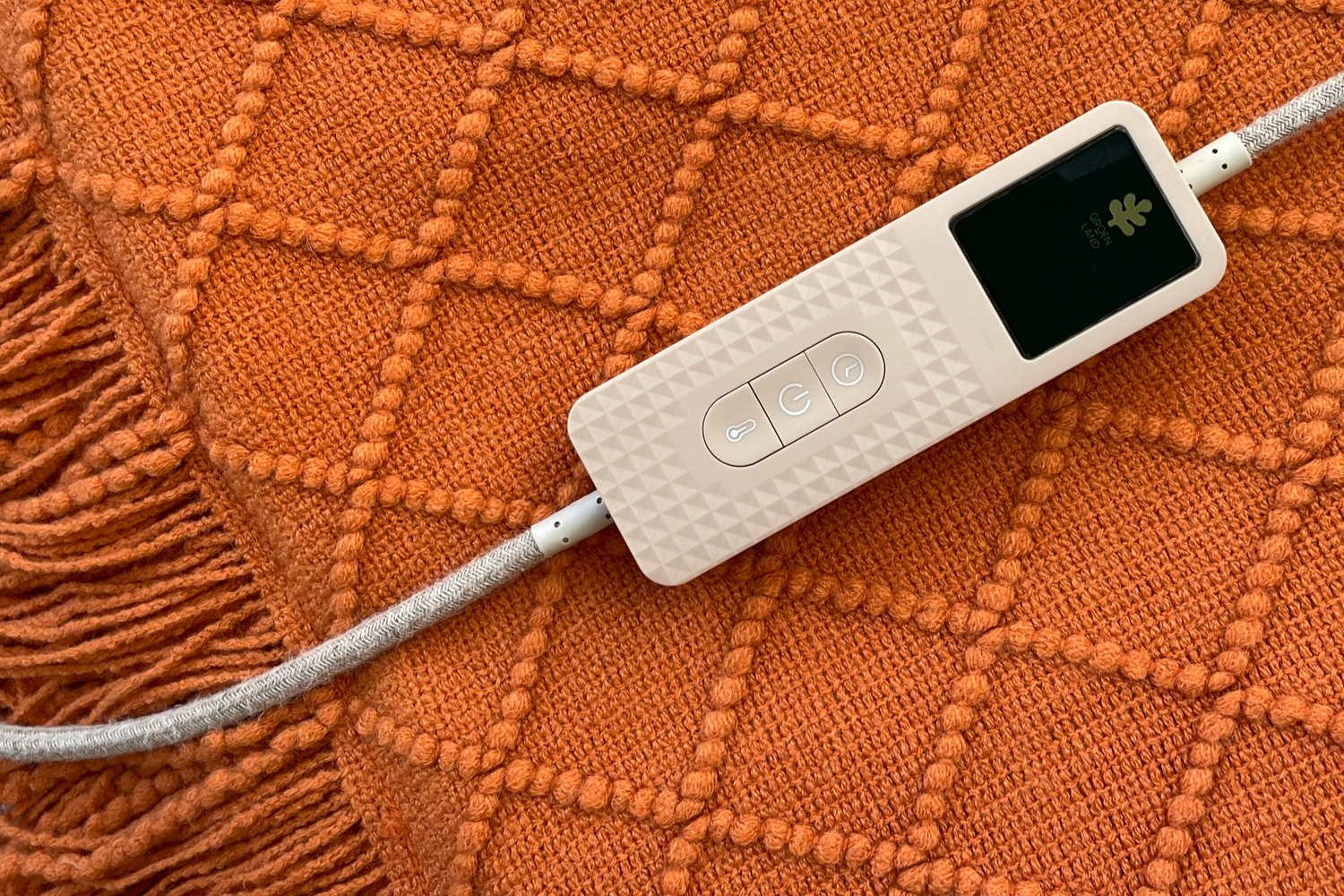 Taupe controller with logo Groenland on an natural Red Earth woolen Heated Sofa Blanket