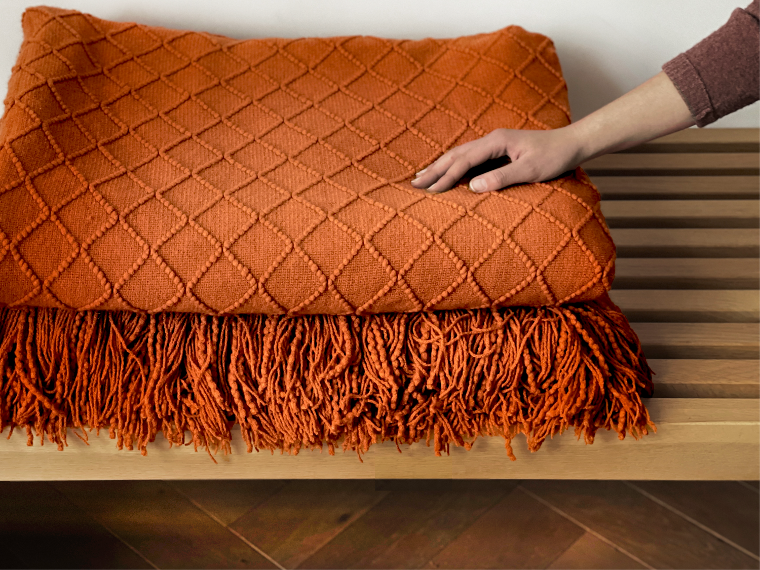 Red Earth knitted heated blanket with fringes on a wooden surface
