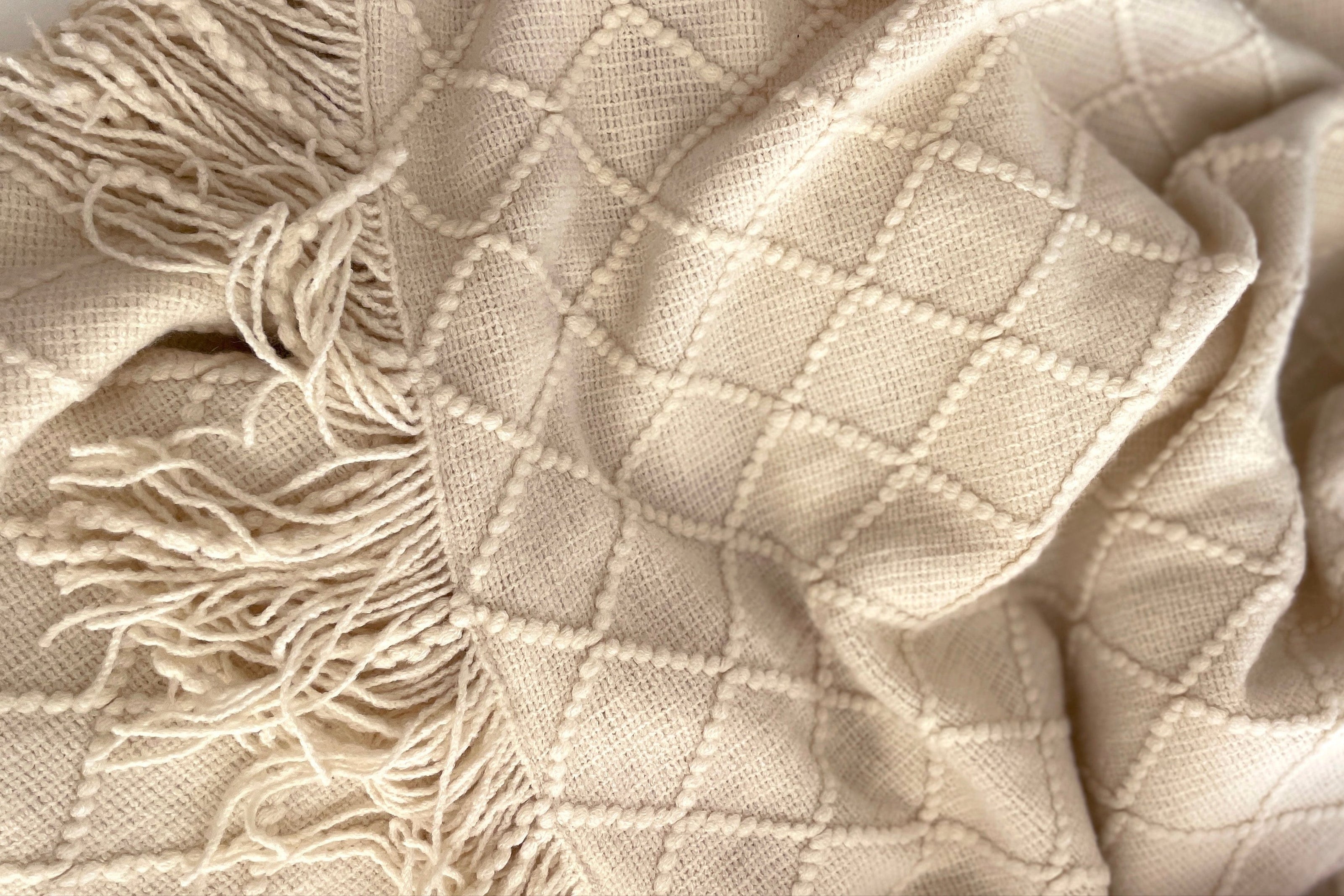 Clay white knitted heated  blanket with tassels on a white background