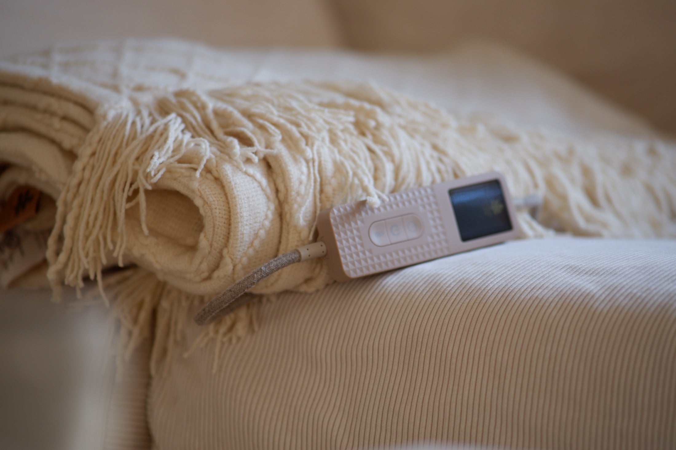 A White Clay BOHEM folded on the sofa with its controller